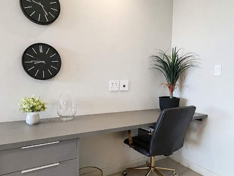 A modern home office space featuring a sleek built-in desk with integrated cabinetry and neutral tiled flooring.