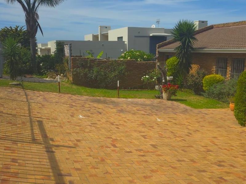 Front exterior view of the apartment featuring a paved driveway, brick facade, and secure perimeter fencing.