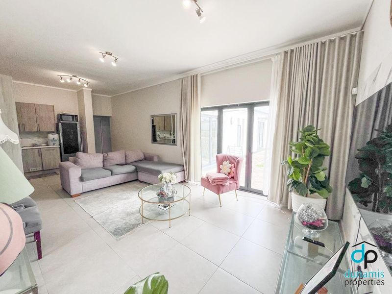 A bright open-plan living area featuring large format floor tiles, modern kitchen cabinetry, and expansive sliding glass doors leading to the exterior.