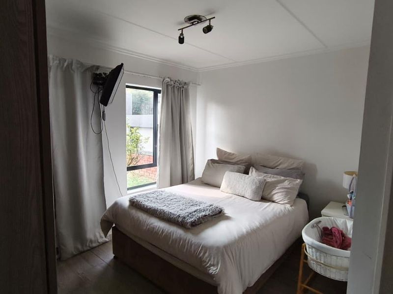A functional bedroom featuring neutral walls, a window with curtains, and ceiling-mounted spotlighting.