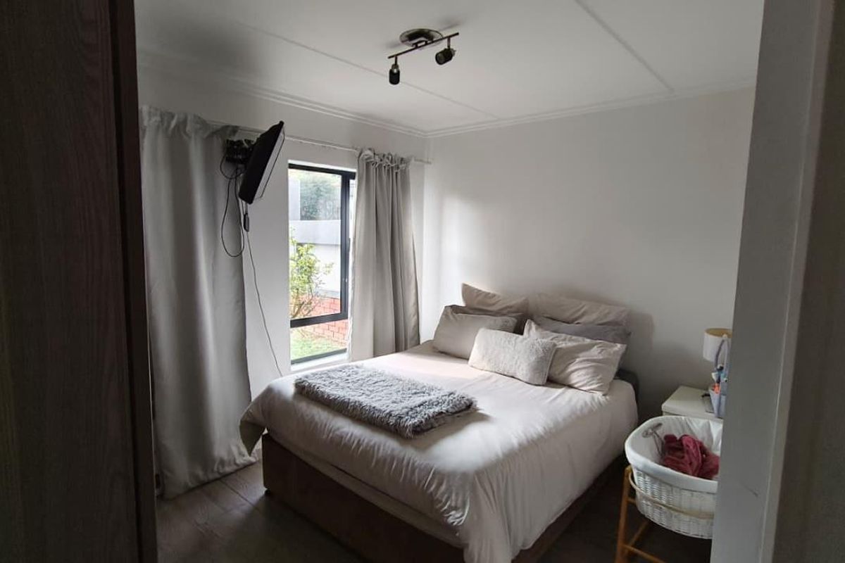 A functional bedroom featuring neutral walls, a window with curtains, and ceiling-mounted spotlighting.