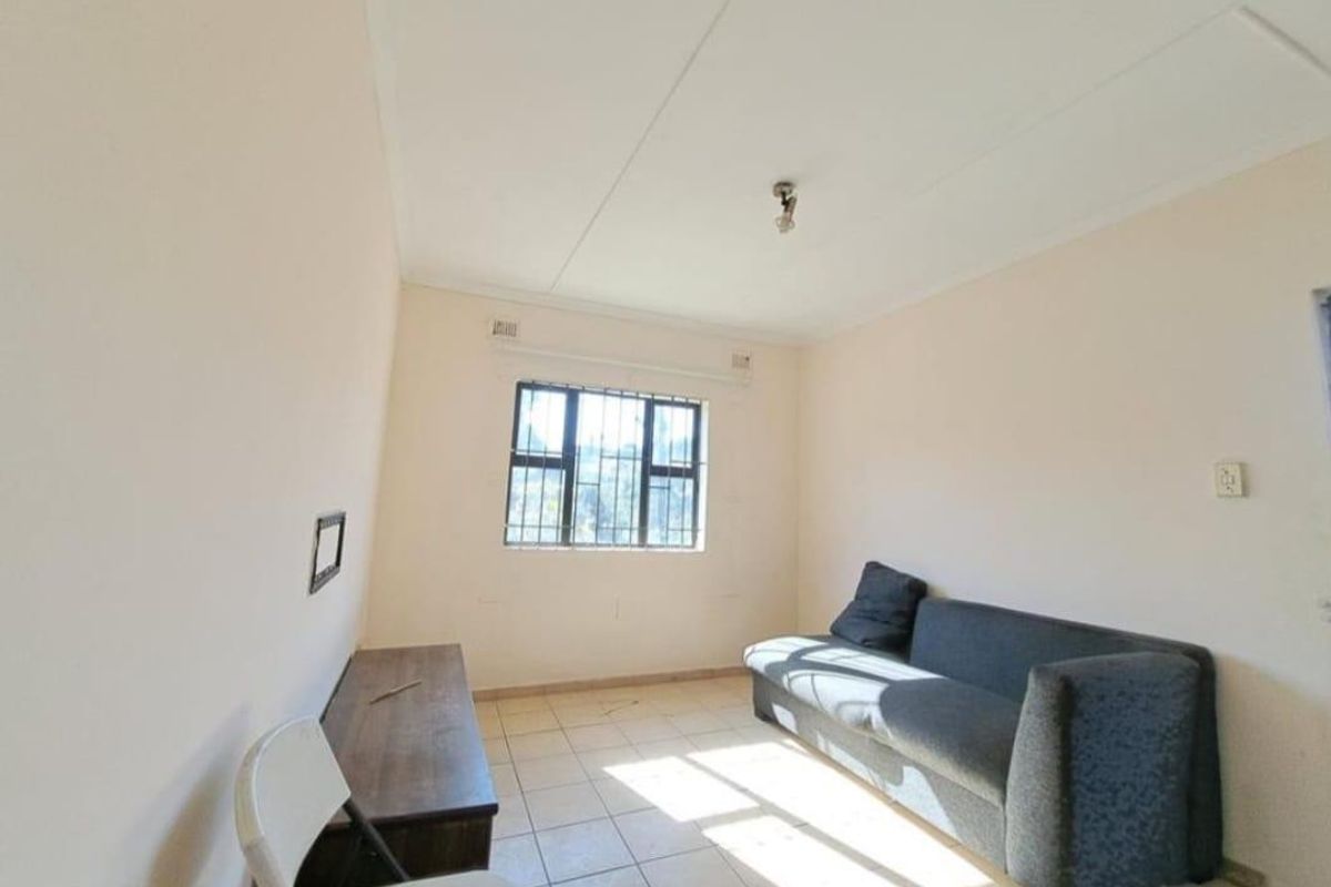 A simple living room featuring tiled flooring and a window with security bars, offering a blank canvas for potential interior updates.