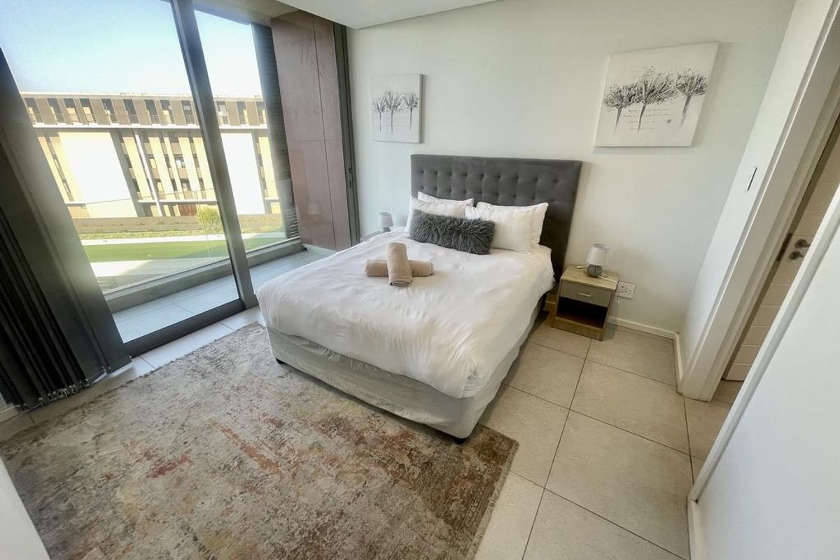 Modern bedroom featuring large floor-to-ceiling sliding glass doors that provide ample natural light and access to an outdoor balcony area.