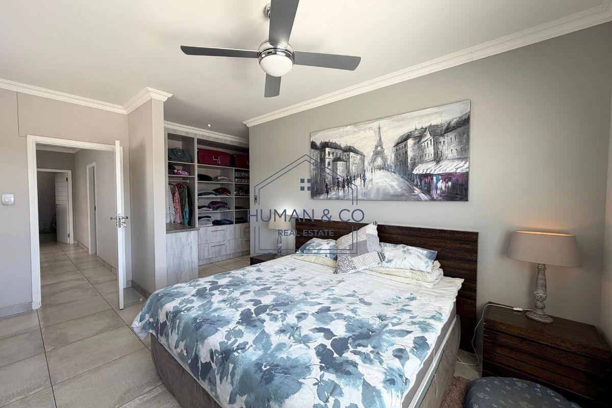 A well-maintained bedroom featuring built-in cupboards, tiled flooring, and a modern ceiling fan, offering a clean and functional living space.