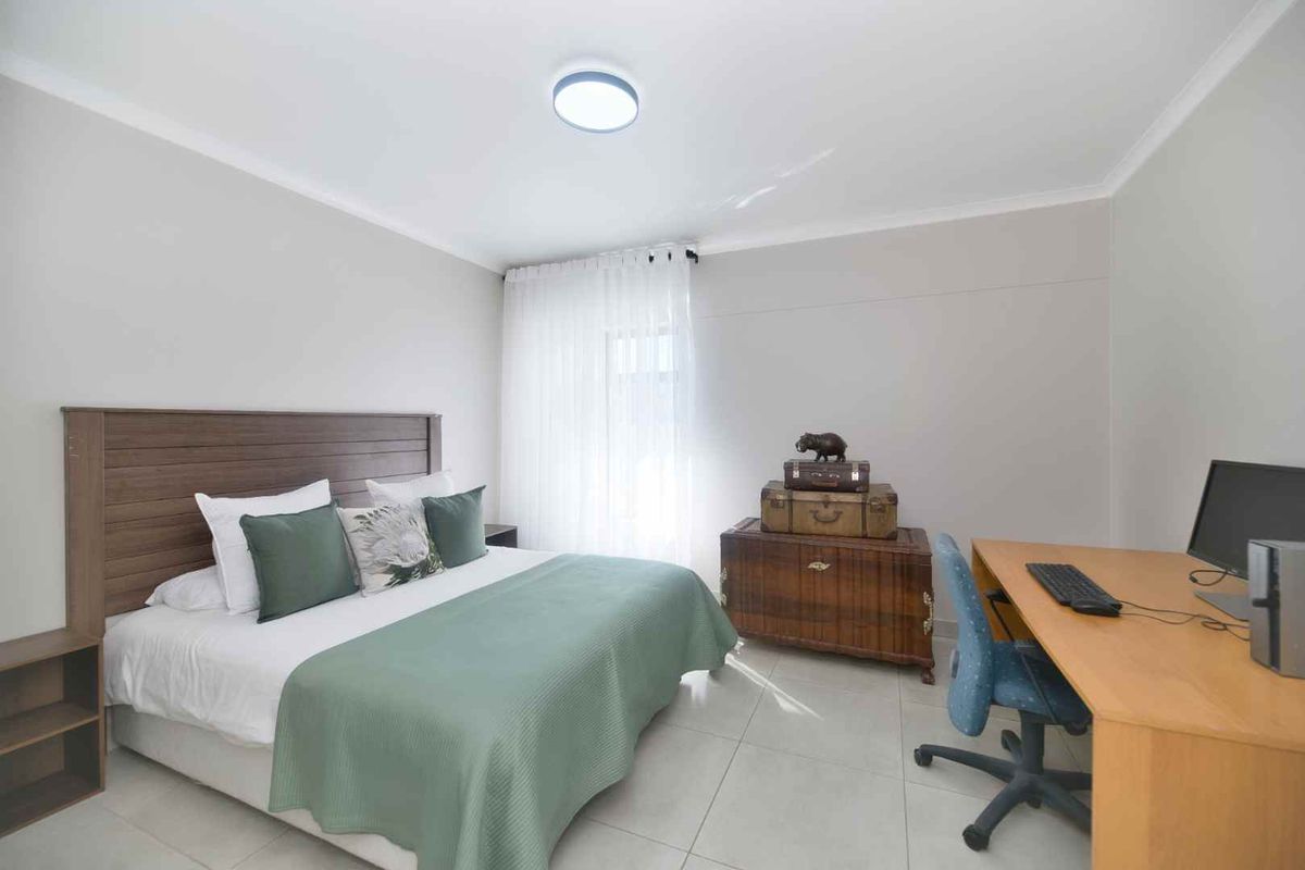 A well-maintained bedroom featuring neutral wall tones, tiled flooring, and a flush mount ceiling light, offering a clean and functional living space.