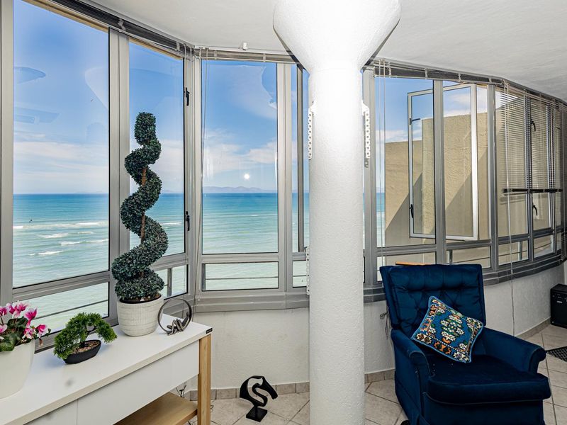 Enclosed balcony area featuring expansive ocean views, large windows, and a structural column, providing a bright and airy space.
