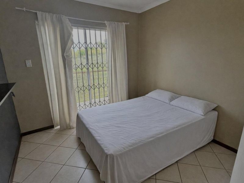 A bedroom featuring tiled flooring, a built-in cupboard, and a sliding glass door with a security gate leading to the exterior.