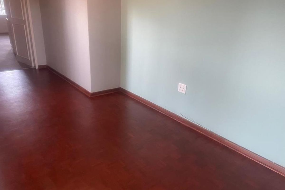 An empty bedroom featuring traditional parquet flooring, light-colored walls, and standard electrical fixtures, ready for personalization.