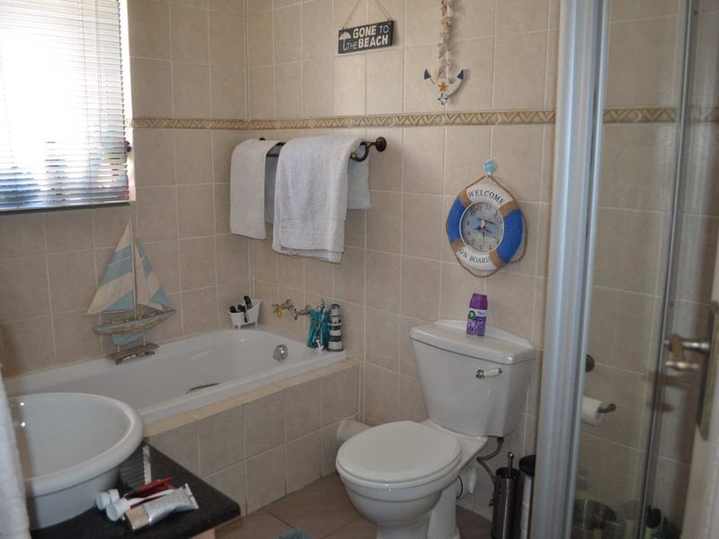 A functional bathroom featuring a bathtub, separate shower enclosure, toilet, and vanity basin with neutral wall and floor tiling.
