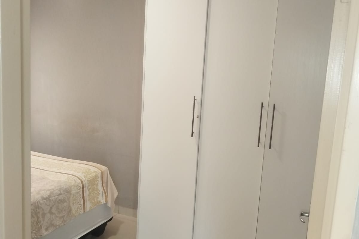 A bedroom featuring tiled flooring and a modern white built-in wardrobe with sleek handles.