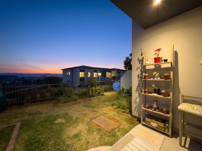 A covered patio area overlooking a private garden and neighborhood at dusk, featuring recessed lighting and concrete flooring.
