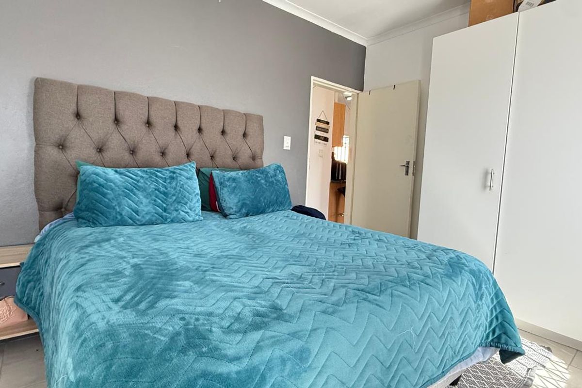A bedroom featuring built-in white wardrobes and a grey accent wall, providing functional storage and a neutral base for the space.