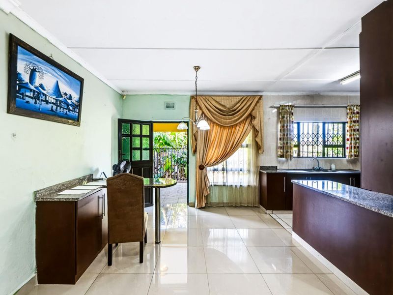 Open-plan kitchen and dining area featuring tiled flooring, granite countertops, and direct access to an outdoor patio space.