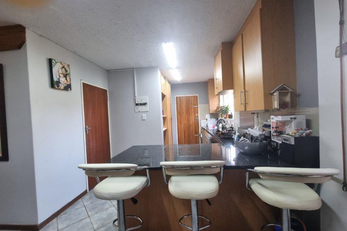 A functional kitchen featuring a central granite-topped breakfast island, wooden cabinetry, and tiled flooring, providing a practical workspace for daily meal preparation.