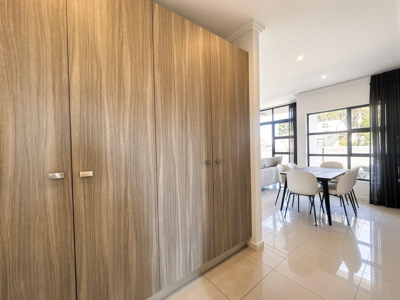Modern open-plan living area featuring sleek built-in cabinetry, polished tiled flooring, and large windows that provide ample natural light.