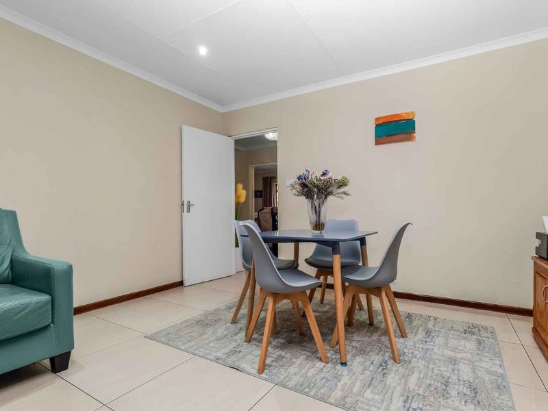 A neutrally painted living area featuring tiled flooring, coved ceilings, and recessed lighting, providing a functional and well-maintained space.