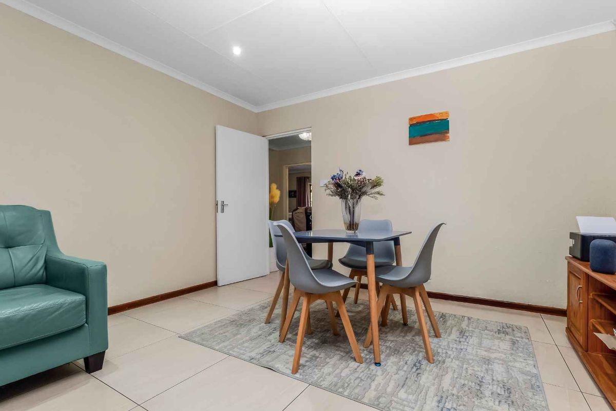 A neutrally painted living area featuring tiled flooring, coved ceilings, and recessed lighting, providing a functional and well-maintained space.