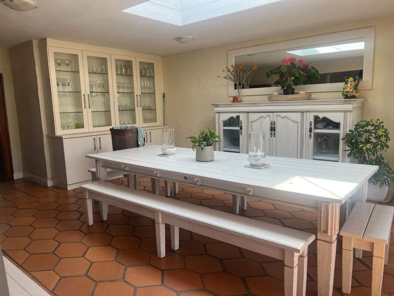 A bright dining room featuring terracotta floor tiles, a large skylight, and extensive built-in cabinetry for storage and display.