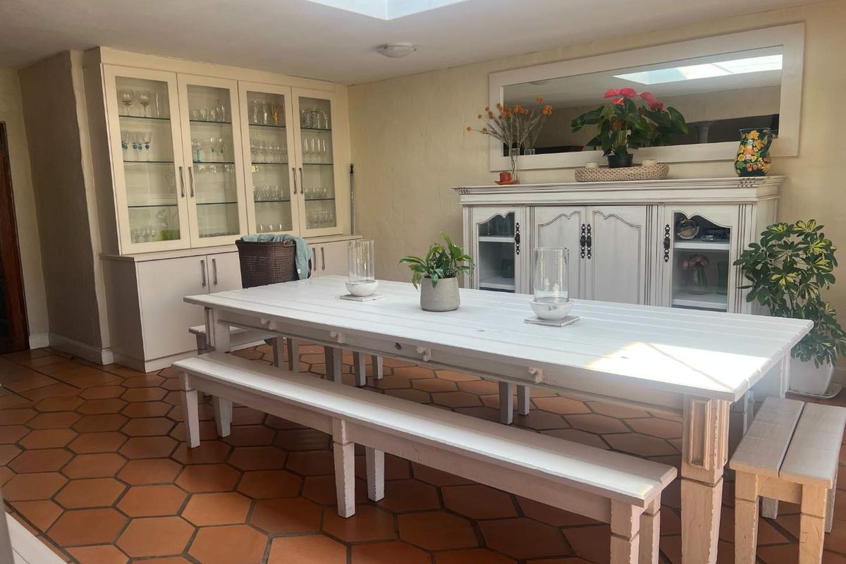A bright dining room featuring terracotta floor tiles, a large skylight, and extensive built-in cabinetry for storage and display.