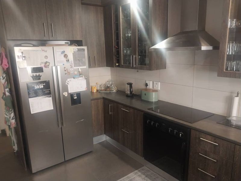 A functional kitchen featuring dark wood-finish cabinetry, stone countertops, a built-in oven, hob, and stainless steel extractor fan.