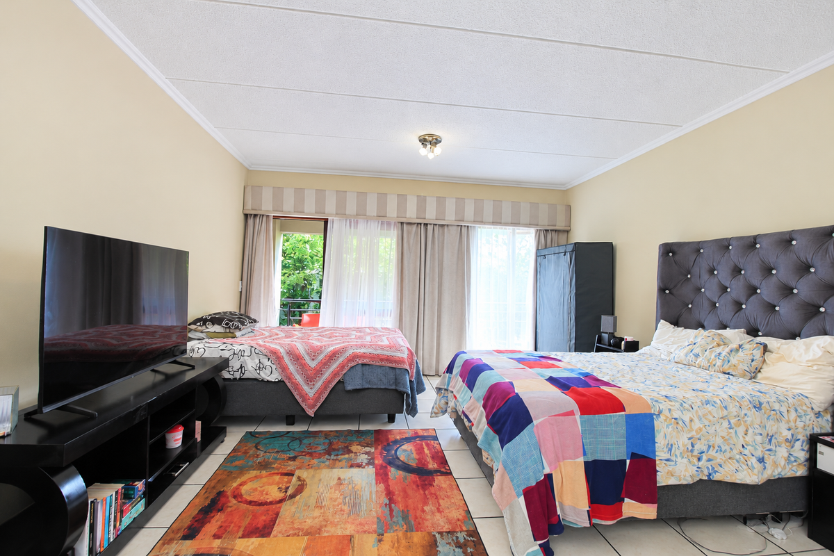 Spacious bedroom featuring tiled flooring, neutral wall tones, and direct access to a private balcony through sliding glass doors.