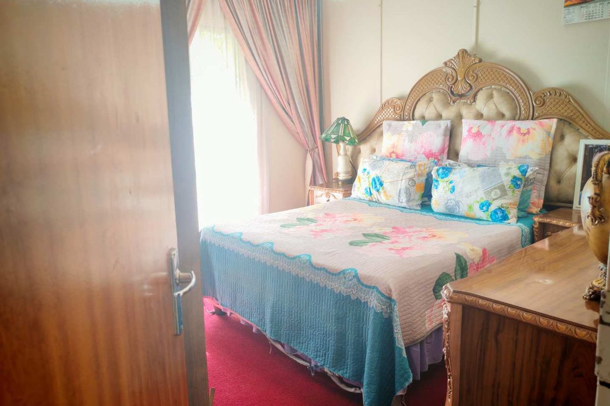 A bedroom featuring carpeted flooring and a window with curtains, providing a functional sleeping space.