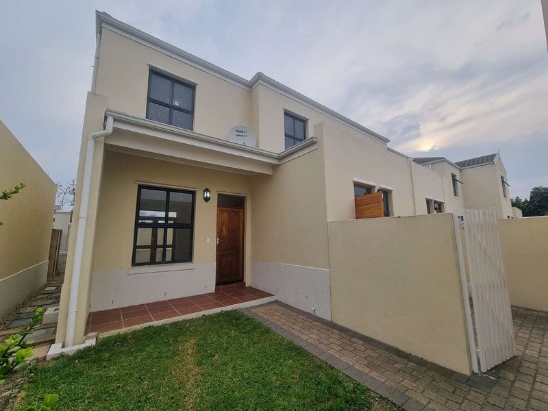 Front elevation of a modern townhouse featuring a paved walkway, tiled entrance porch, timber front door, and low-maintenance garden area.