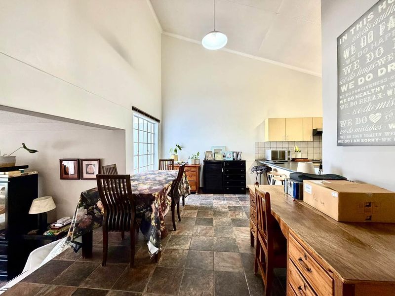 Open-plan living and dining area featuring vaulted ceilings, tiled flooring, and an integrated kitchen space with functional cabinetry.