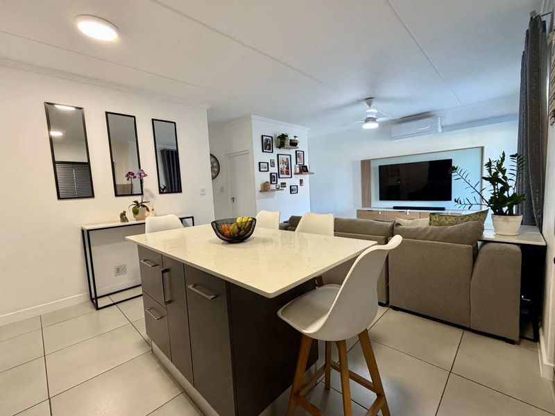 Spacious open-plan living area featuring a modern kitchen island with stone countertops, tiled flooring, and integrated climate control.