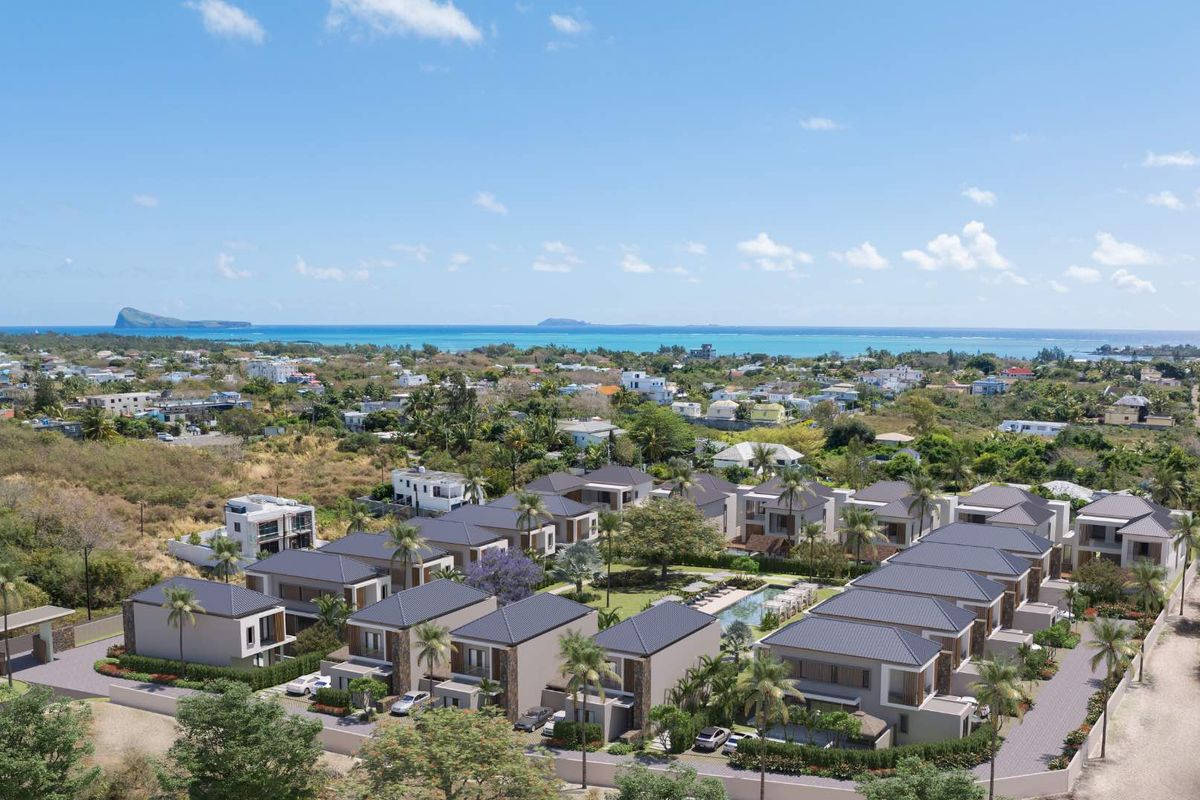Aerial view of a modern residential estate featuring multiple detached houses, landscaped grounds, and a central swimming pool with distant ocean views.