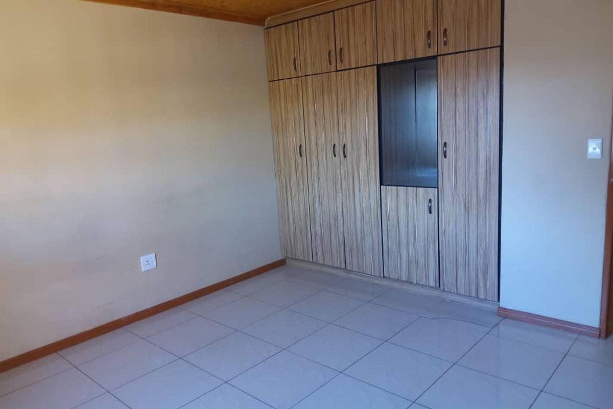 A bedroom featuring tiled flooring and built-in floor-to-ceiling wooden cabinetry with integrated shelving.