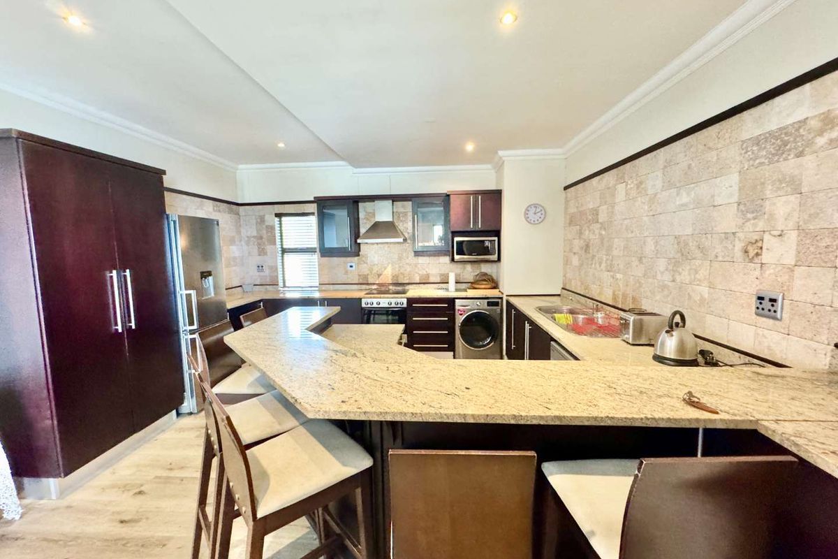 A functional kitchen featuring granite countertops, a breakfast bar, built-in cabinetry, an integrated oven, and a stone-tiled backsplash.