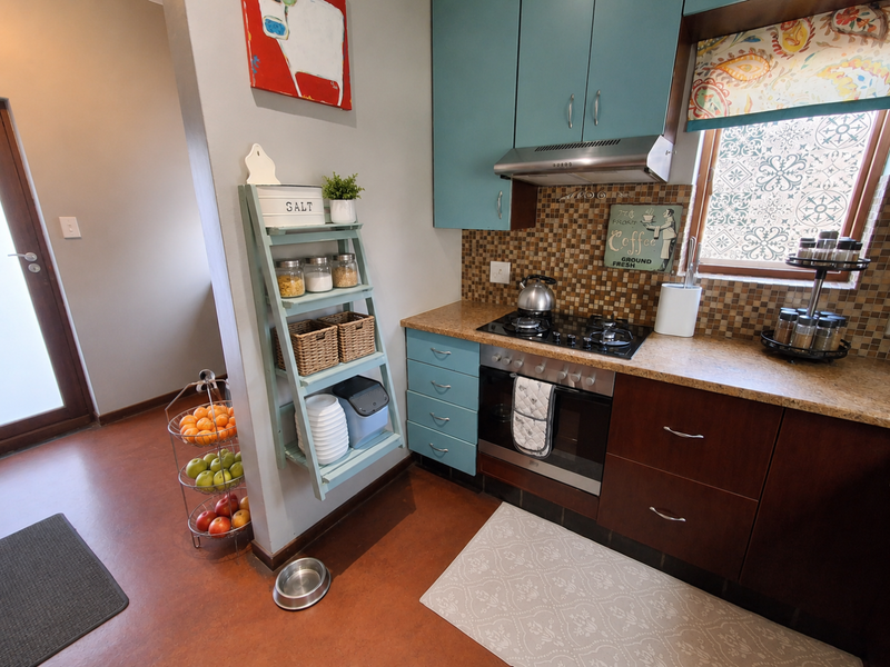 A compact kitchen featuring blue and dark wood cabinetry, a mosaic tile backsplash, built-in oven, and gas cooktop.