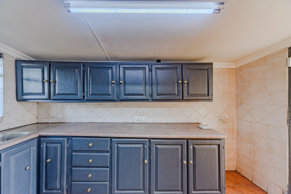 A functional kitchen area featuring dark blue built-in cabinetry, tiled backsplash, and a stainless steel sink, offering a blank canvas for modern updates.