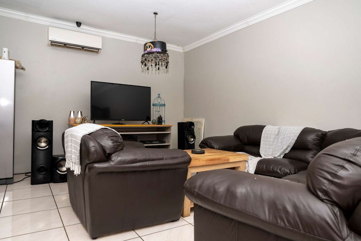 A living room featuring tiled flooring, crown molding, and a wall-mounted air conditioning unit.