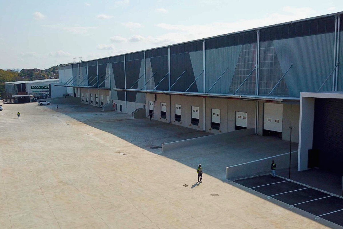 Aerial view of a modern industrial warehouse featuring multiple loading docks, roller shutter doors, and a spacious concrete yard for logistics operations.