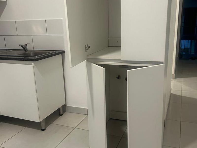 A clean, modern laundry area featuring built-in cabinetry, tiled flooring, and a functional sink with a tiled splashback.