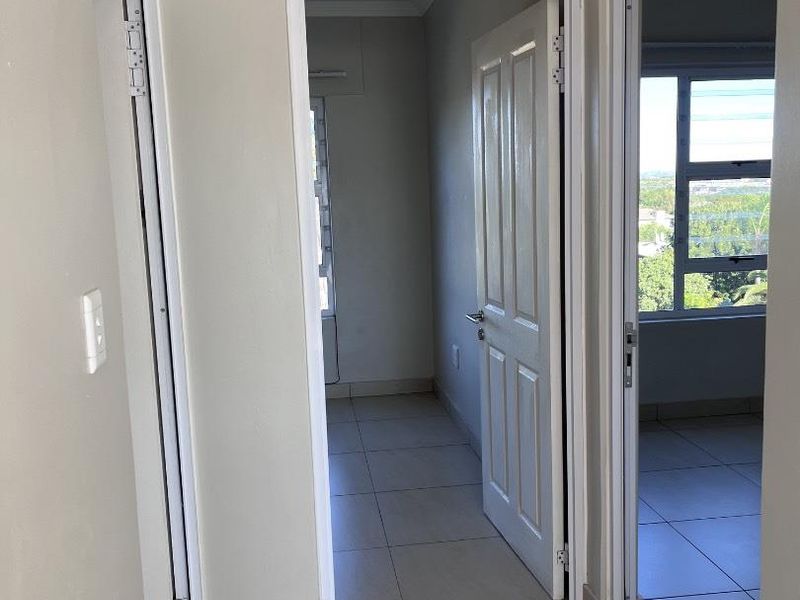 A bright, neutral-toned hallway featuring tiled flooring and access to multiple rooms, providing a clean and functional transition space within the townhouse.