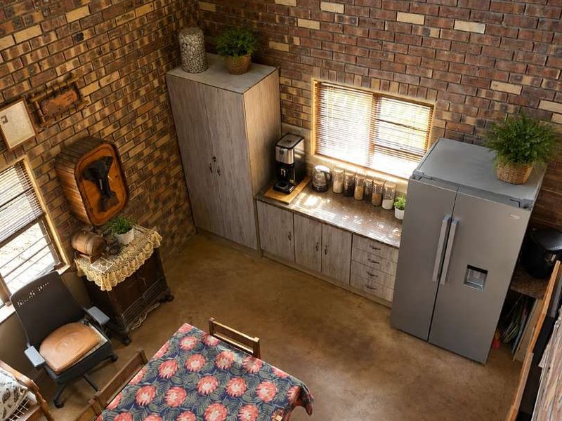 Open-plan living and kitchen area featuring high ceilings, exposed brick walls, polished concrete floors, and built-in cabinetry with a modern industrial aesthetic.