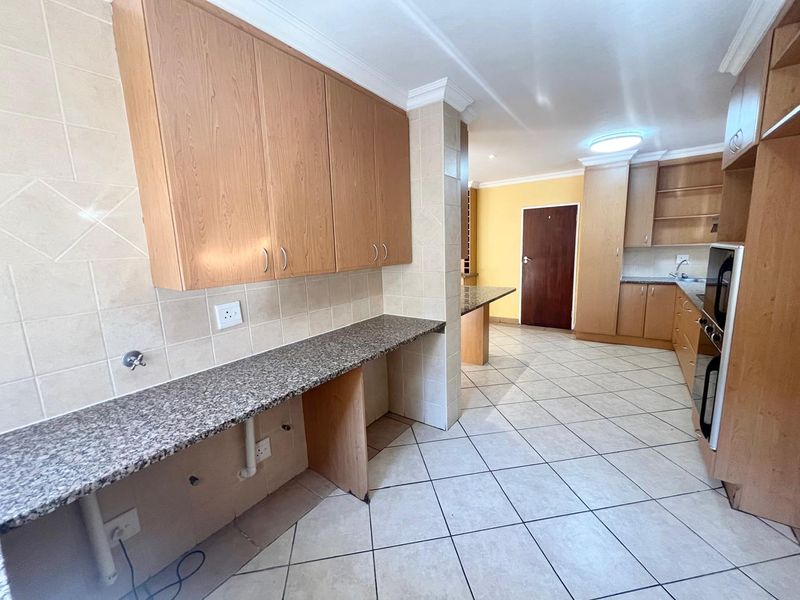 Spacious kitchen featuring granite countertops, ample wooden cabinetry, tiled flooring, and a built-in oven, offering a functional layout for culinary activities.