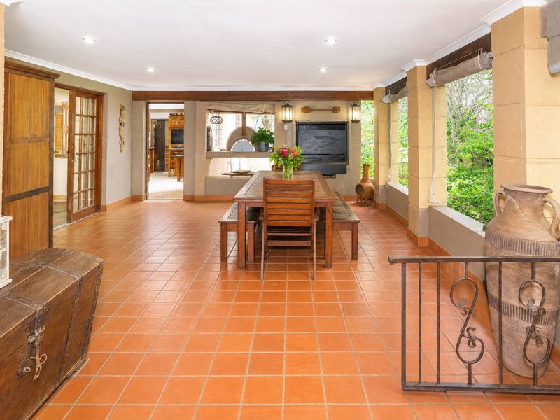 Spacious covered patio featuring terracotta tiling, a built-in braai area, and direct access to the interior, perfect for outdoor entertaining.