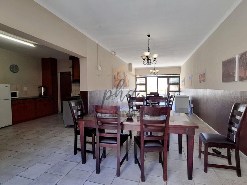 Spacious open-plan dining and kitchen area featuring tiled flooring, built-in cabinetry, and direct access to the outdoor space through sliding glass doors.