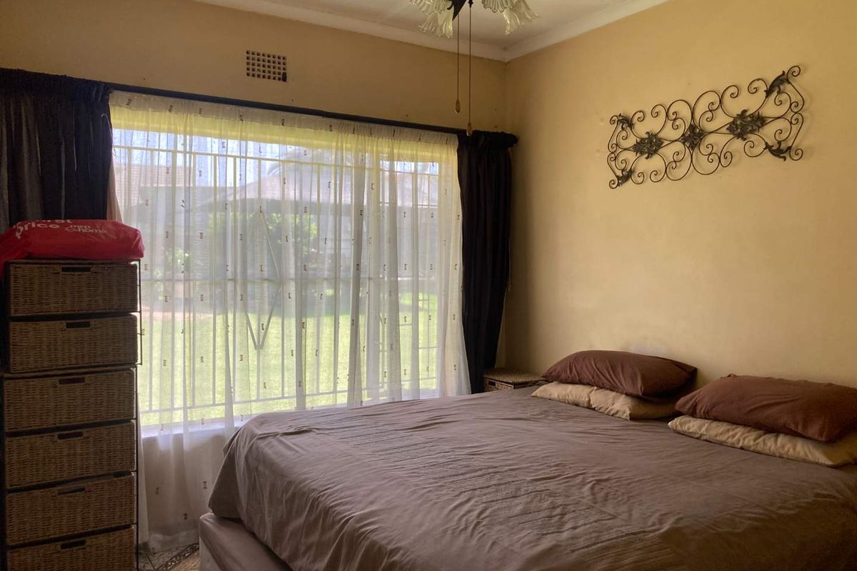 A bedroom featuring a ceiling fan, large window with natural light, and tiled flooring.