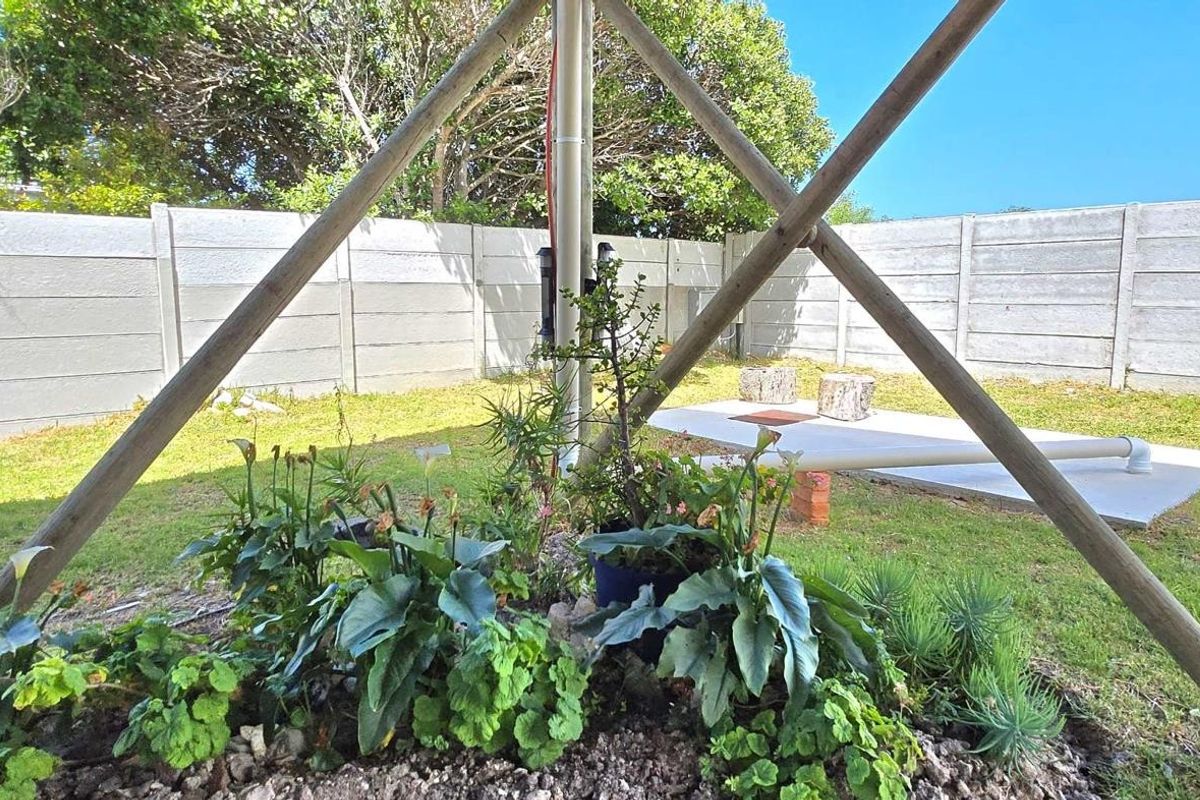 A rear garden area featuring a concrete slab, perimeter precast concrete walling, and a central structural support frame.
