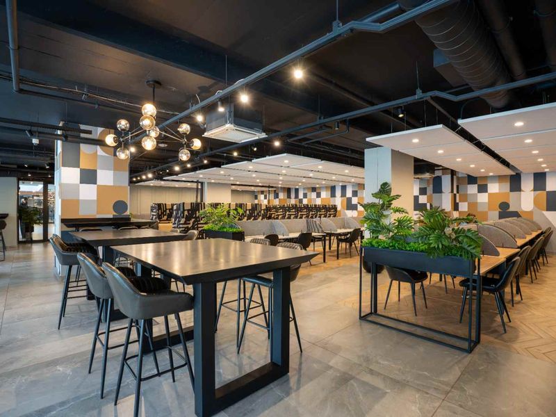 Modern, well-appointed clubhouse area featuring industrial-style exposed ceilings, contemporary geometric wall finishes, and high-quality tiled flooring suitable for communal use.