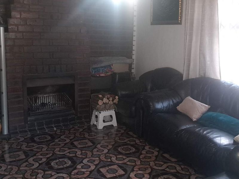 Living room featuring a prominent brick fireplace and patterned tiled flooring, offering a cozy and traditional atmosphere.