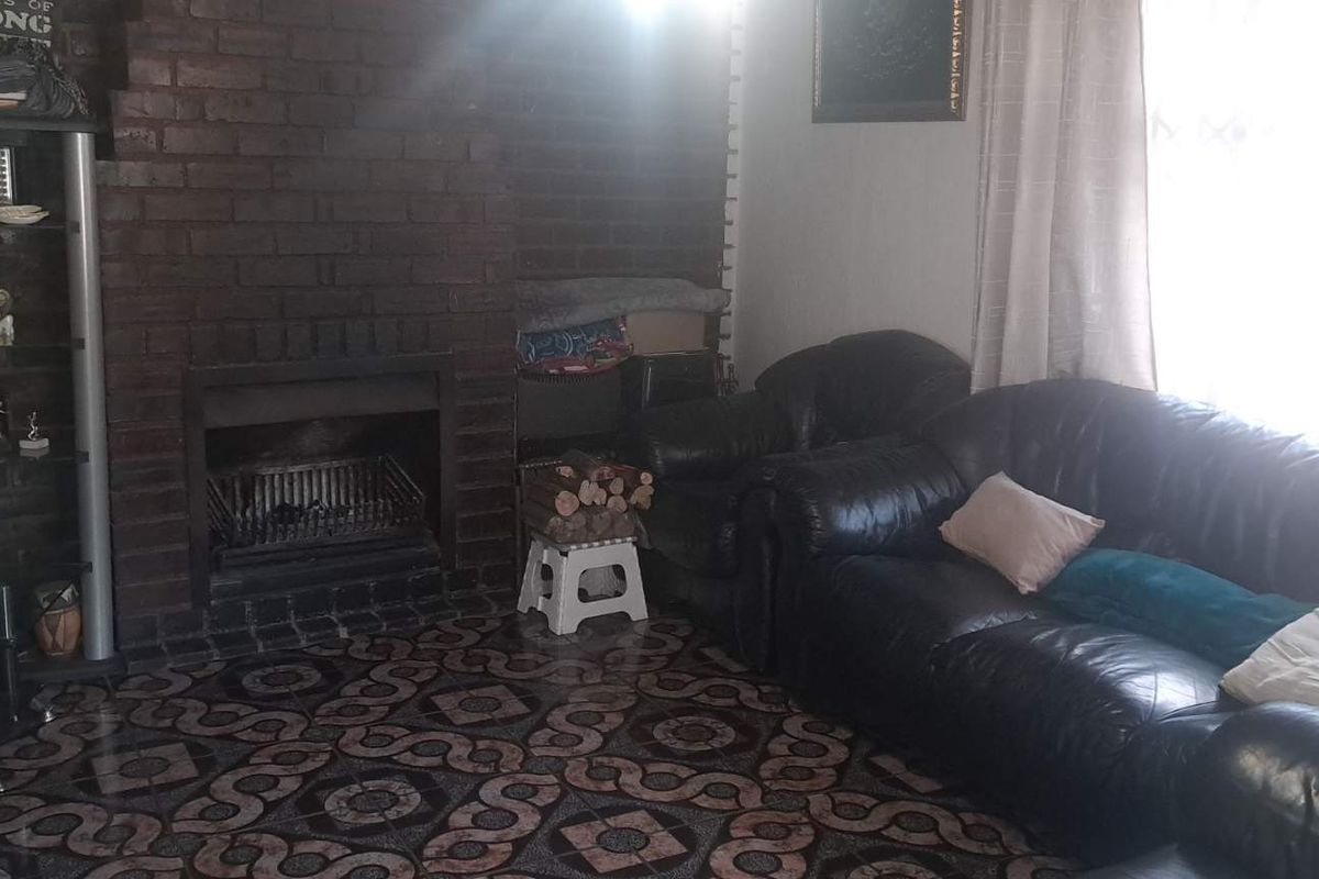 Living room featuring a prominent brick fireplace and patterned tiled flooring, offering a cozy and traditional atmosphere.