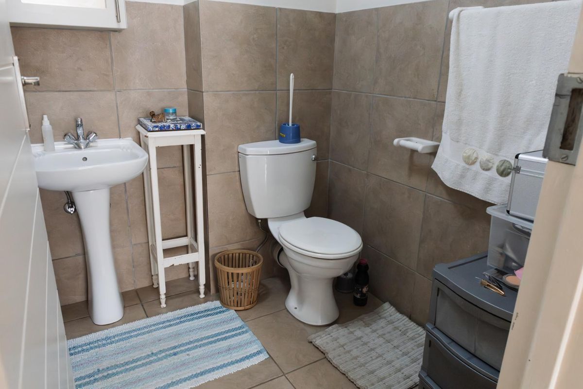 A functional bathroom featuring a pedestal basin, a standard toilet, and neutral wall tiling.