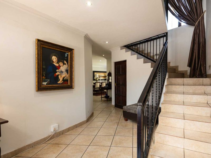 Welcoming entrance hall featuring tiled flooring, a staircase with a wrought iron balustrade, and recessed downlighting, leading into the main living areas.