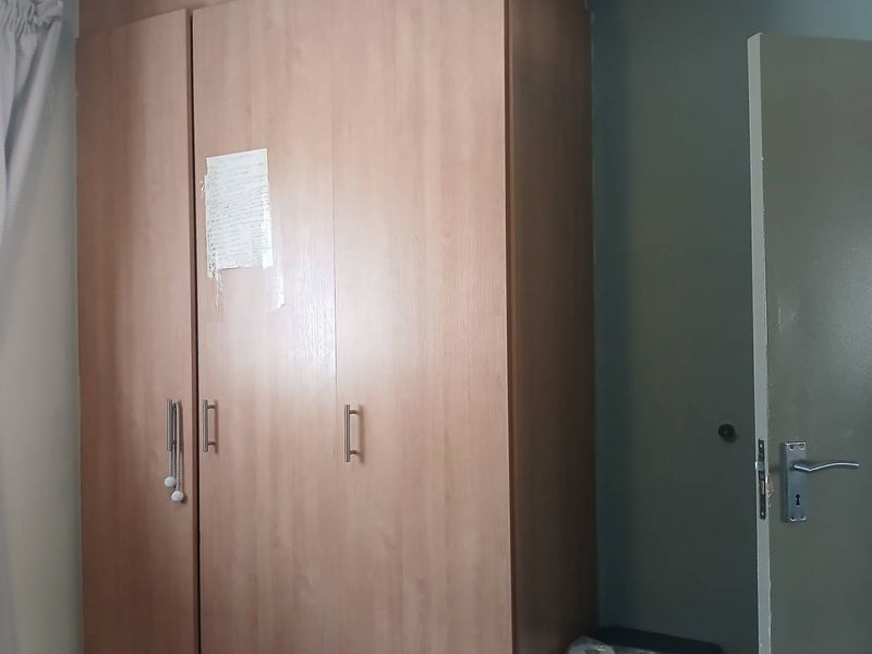 A bedroom featuring a built-in wooden wardrobe and a standard internal door.